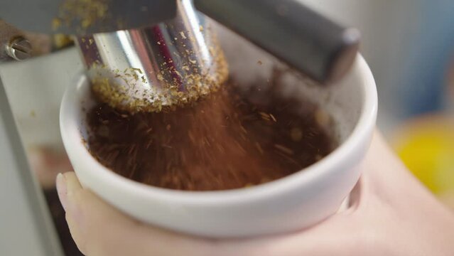 Barista uses grinder machine to grind fresh coffee beans, extreme macro close up