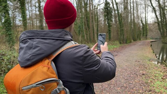 Tourist Makes photo of Nature using smartphone, holding digital device. Male Backpacker travel, epic beautiful landscape