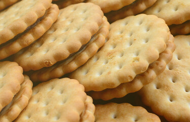 Detailed picture of round sandwich cookies with coconut filling. Background image of a close-up of several treats for tea