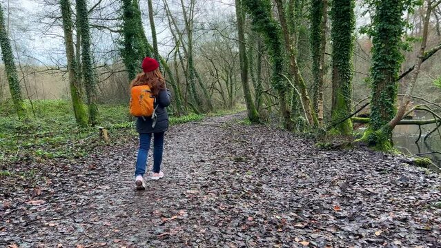 Tourist Travel Woman Walking in woods with orange backpack, female with red long hair backpacking traveler making photo of beautiful lake forest nature landscape 