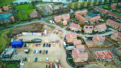 Fotobehang Aerial view of a residential area with ongoing construction, showcasing houses, roads, and construction equipment. © Vas