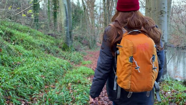 Tourist Travel Woman Walking in woods with orange backpack, female with red long hair backpacking traveler making photo of beautiful lake forest nature landscape 