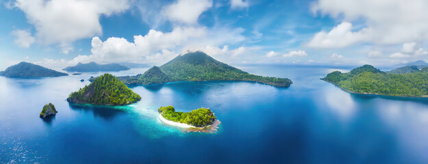 Lush green islands surrounded by the vibrant blue of the Indonesian sea in the Moluccas create a...