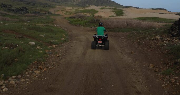 Following behind four wheeler on dirt road at dusk