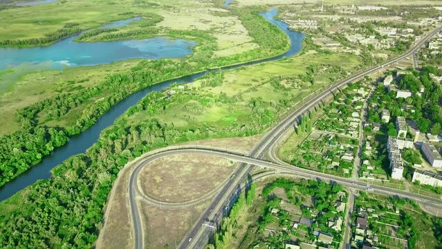 Aerial view of highway cross road junction at daytime. Cars are moving along the road junction. Urban infrastructure concept