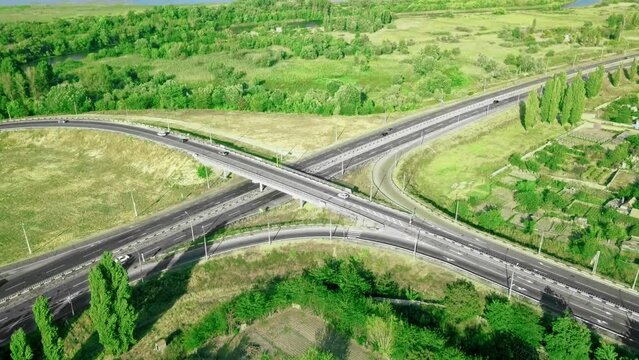 Aerial view of highway cross road junction at daytime. Cars are moving along the road junction. Urban infrastructure concept