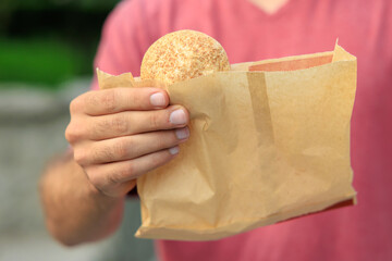 Guy's hand holds mini bread, snack and fast food concept. Selective focus on hands with blurred background