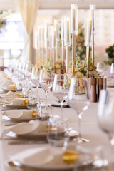 Serving the festive table at a wedding event. Decorating the wedding table with bouquets of...
