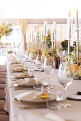 Serving the festive table at a wedding event. Decorating the wedding table with bouquets of flowers. Cutlery at a party 