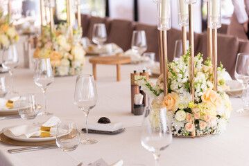 Serving the festive table at a wedding event. Decorating the wedding table with bouquets of flowers. Cutlery at a party 