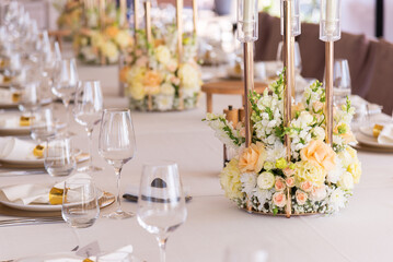 Serving the festive table at a wedding event. Decorating the wedding table with bouquets of flowers. Cutlery at a party 