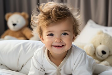 A charming smiling baby in a white sunny bedroom. A baby crawling in bed. Nursery for small children. Textiles and bed linen for children. Family morning at home.