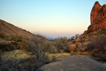 Large boulders are scattered along the rocky mountain slope. Blue sky above