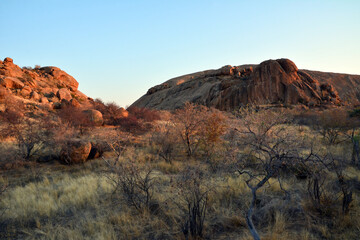 Large boulders are scattered along the rocky mountain slope. Blue sky above