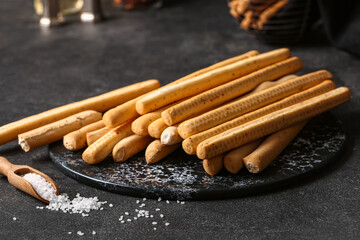 Slate board with tasty Italian Grissini on dark background