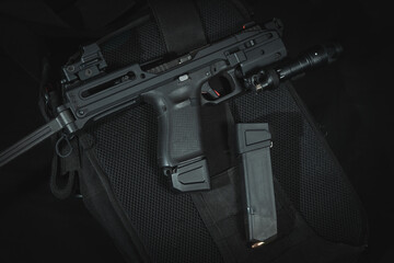Tactical pistol with a stock and a flashlight, close-up photo on a black background. - obrazy, fototapety, plakaty