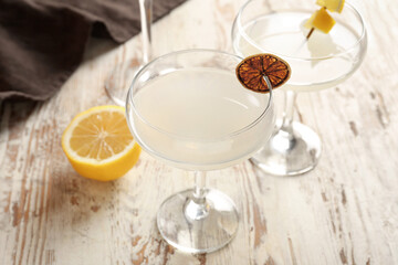 Glasses of martini with lemon on light wooden background