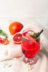 Glass of tasty blood orange lemonade on light background