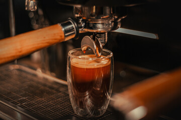 coffee maker making American coffee in glass cup with coffee foam