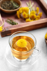 Glass cup of healthy dandelion tea on white background