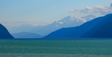 Snowcapped mountains overlooking over the waters of the Taiya Inlet in the Pacific Ocean near...