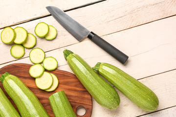 Board with many fresh green zucchini on white wooden background