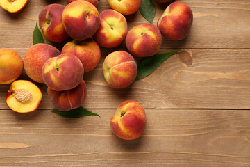 Many sweet peaches and leaves on wooden background