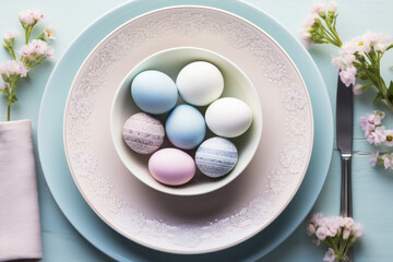 Top view photo of pastel easter eggs in plate on table, cutlery and flowers