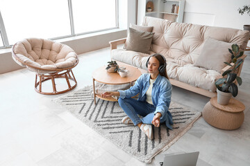 Young woman with headphones meditating on carpet in living room