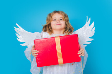 Kid boy angel with gift box present. Kid wearing angel costume white dress and feather wings....