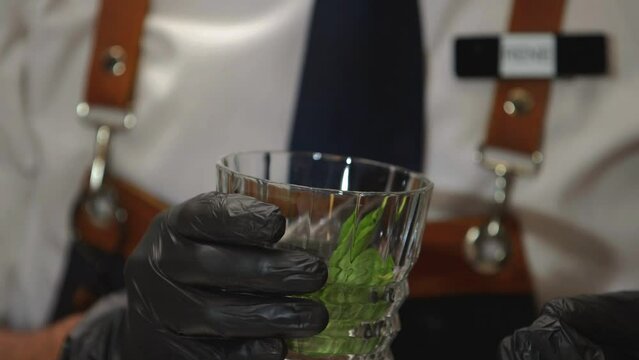 Bartender vertiendo hojas de menta a un vaso