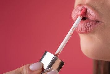 Applying lipstick, macro. Painting lips with bright lipstick, close up. Pampering, lips correction...