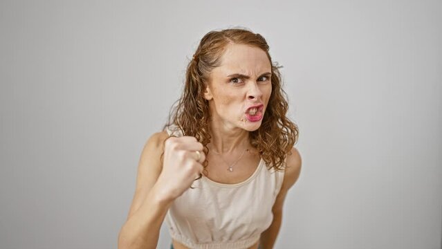 Furious young woman standing enraged, fist clenched in fits of madness. pure anger, frustration from raging fury radiates on an isolated white background.