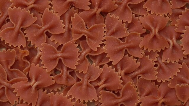 Italian red farfalle pasta background. Table spin.