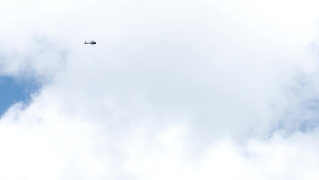 Helicopter tour above Oahu island. Tourists flying in helicopter above scenic Hawaiian landscapes on cloudy day. Scenic outdoor adventure tour. USA tourism 4K. View of Helicopter in blue sky in clouds