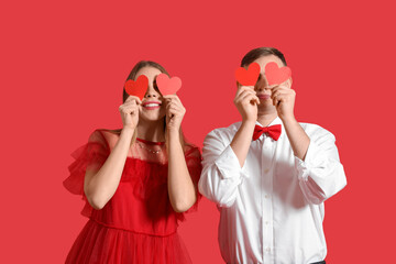 Happy young couple with paper hearts on red background. Valentine's Day celebration