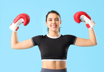 Young woman in boxing gloves on blue background