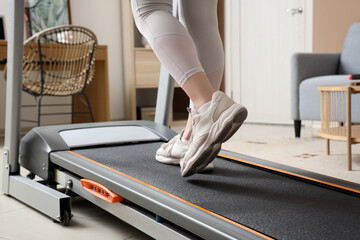 Sporty young woman training on treadmill at home, closeup