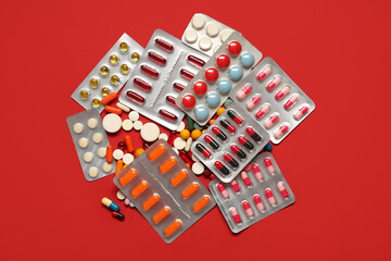 Heap of different pills on red background