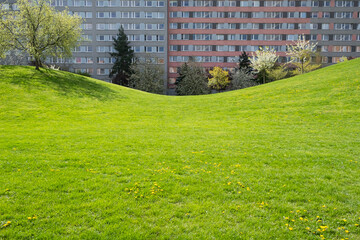 Obraz premium spring in Prague public park against Typical Modern panel made apartment building with plastic windows and thermo insulated walls. Architecture in West Europe. Real estate; green leaving concept.