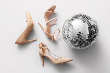 Different high-heeled shoes and disco ball on white background