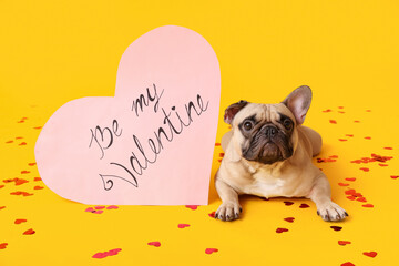 Cute French bulldog and heart shaped card with text BE MY VALENTINE on yellow background. Valentine's Day celebration