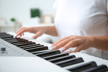 Obraz premium Young woman playing synthesizer at home, closeup