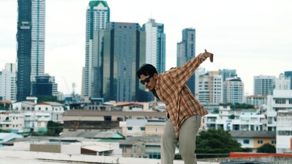 Hispanic break dancer practice B-boy footsteps at roof top with urban city view or sky scrapper....