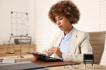 Notary with clipboard writing notes at workplace in office