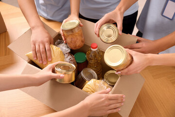 Group of volunteers packing food products at wooden table, above view
