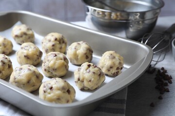 Baking pan with raw chocolate chip cookie balls on table, closeup
