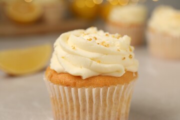 Tasty cupcake with cream and lemon zest on light table, closeup