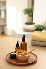 Dry flowers, bottles of essential oils and jar with cream on wooden table indoors, space for text. Spa time