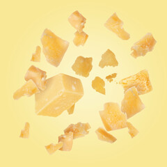 Tasty parmesan cheese falling on light golden background